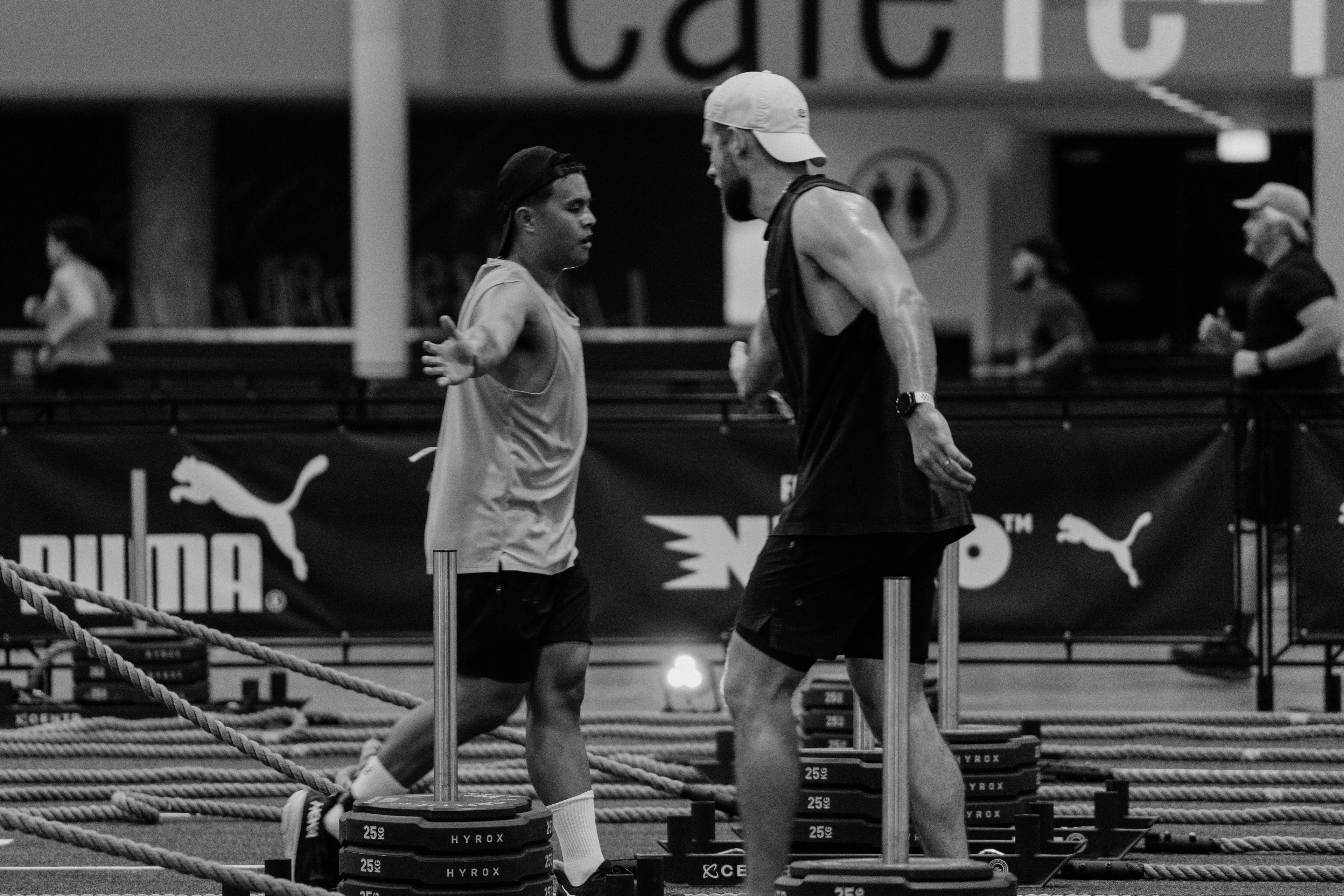 Two athletes greeting each other beside training sleds and ropes.