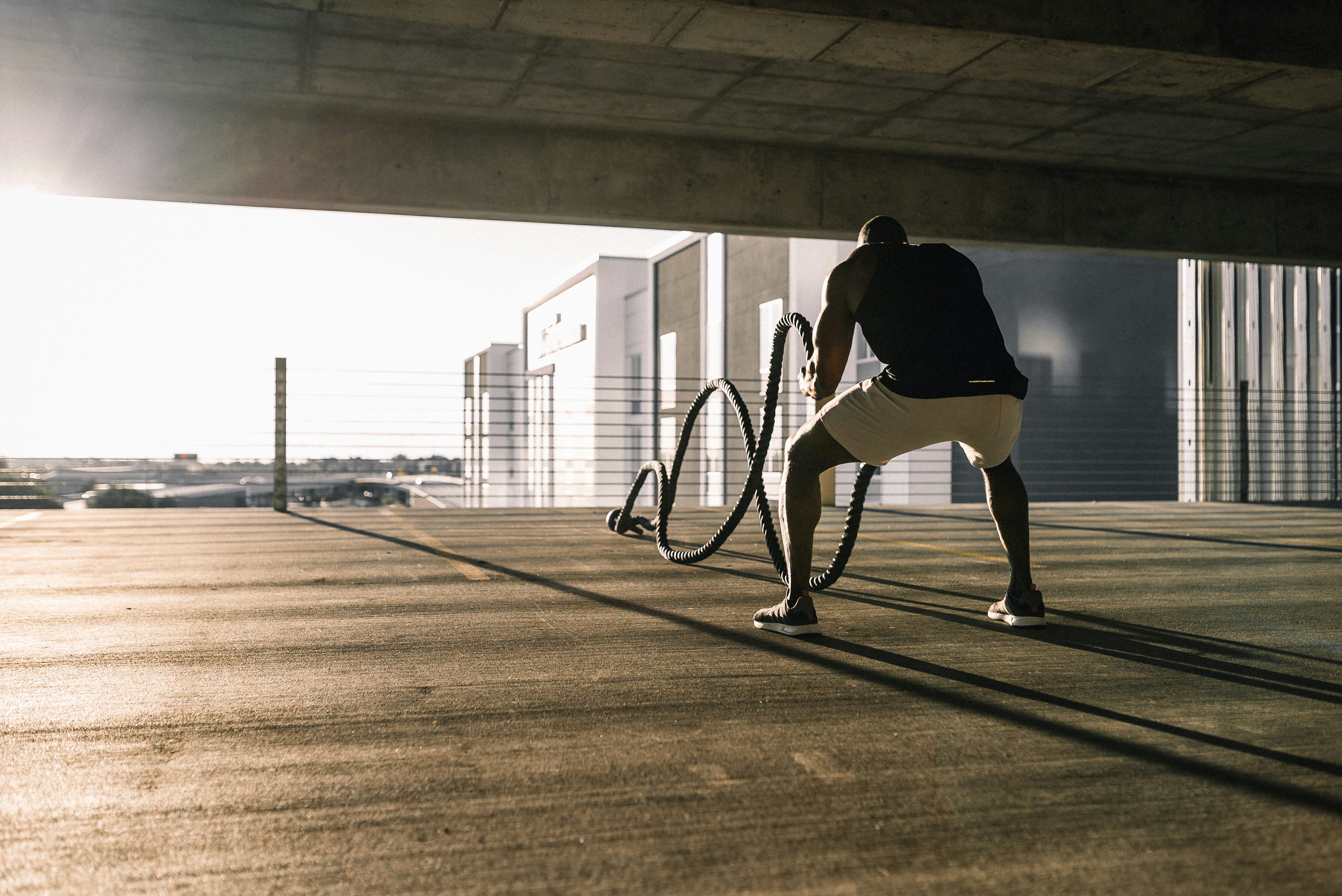 Athlete training with battle ropes in a covered outdoor space.